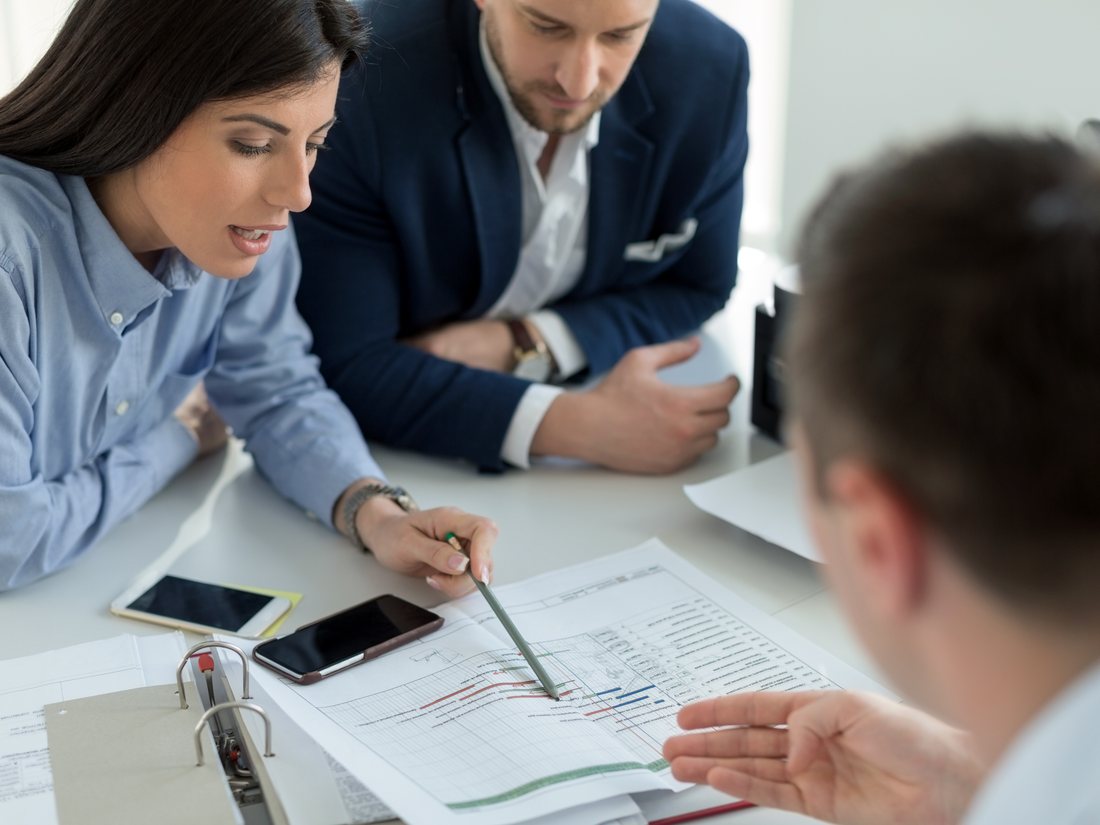 Three colleagues reviewing hiring plans together around a table